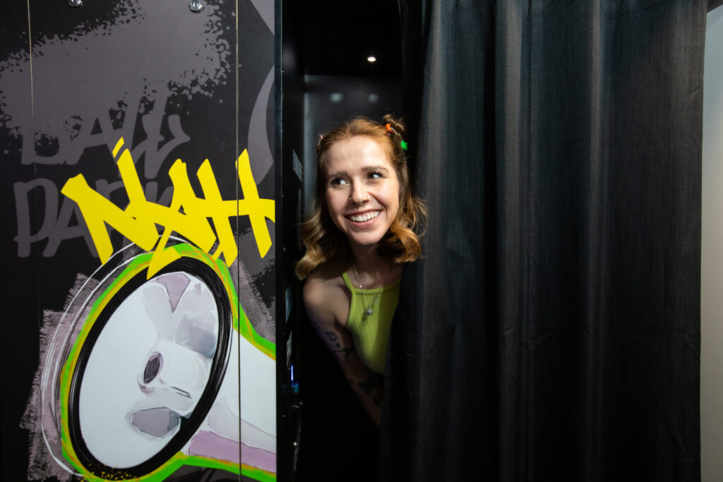 Unit stills photography on location. A woman peers from behind a curtain