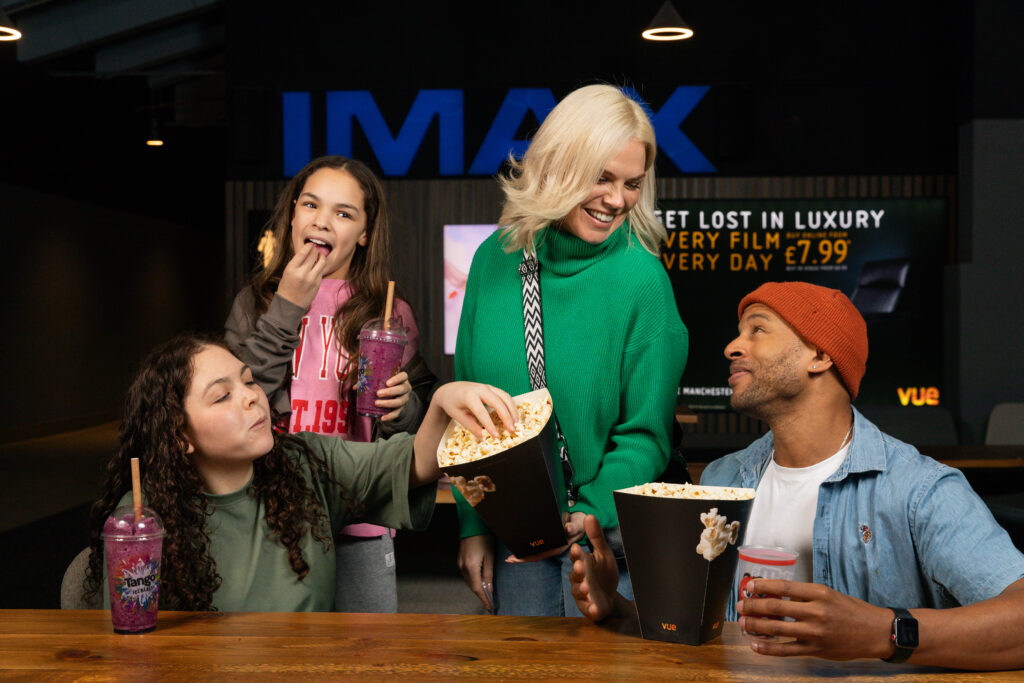 Unit stills photography on location in Manchester. A family enjoy popcorn and drinks at the IMAX