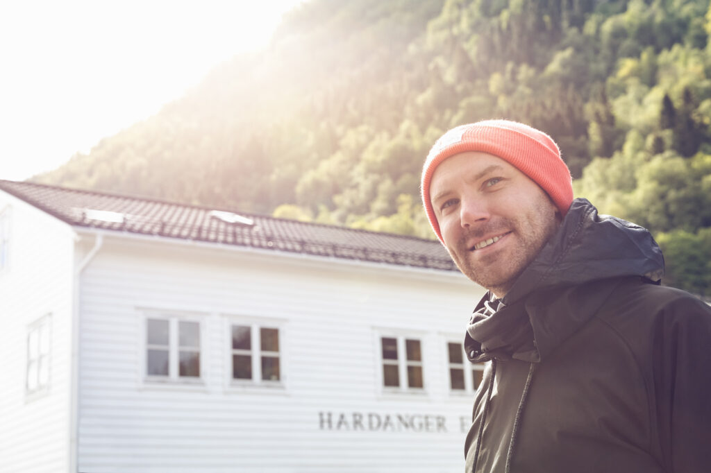 Unit stills photography on location in Norway. A man looks past the camera as the sun rises over a mountain