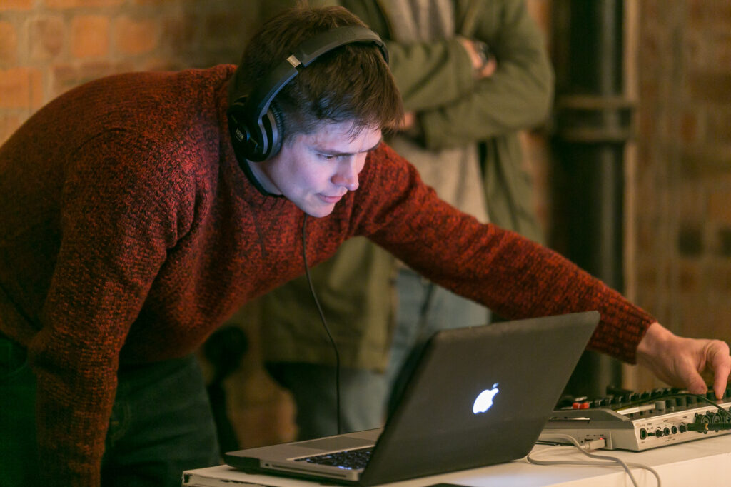 BTS photography on location in Manchester. A man watches playback on a laptop while using audio dials